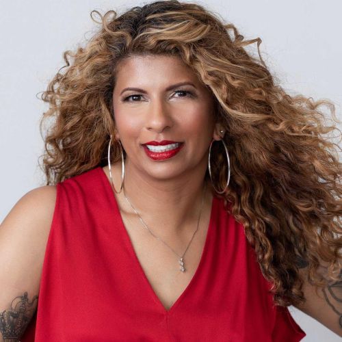 Headshot of Brenda Gilbert, a woman wearing a bright red top, curly hair and a radiant smile.